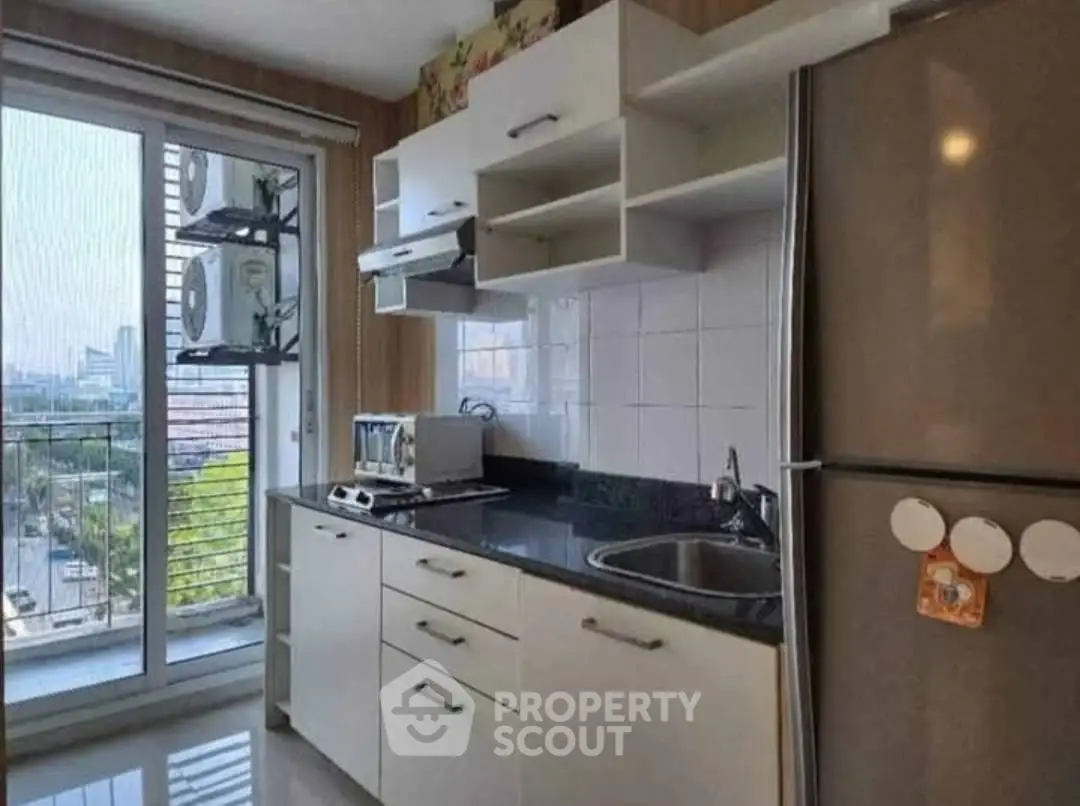 Modern kitchen with sleek cabinetry and city view from balcony, featuring stainless steel appliances.
