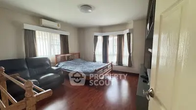 Spacious bedroom with wooden flooring and ample natural light