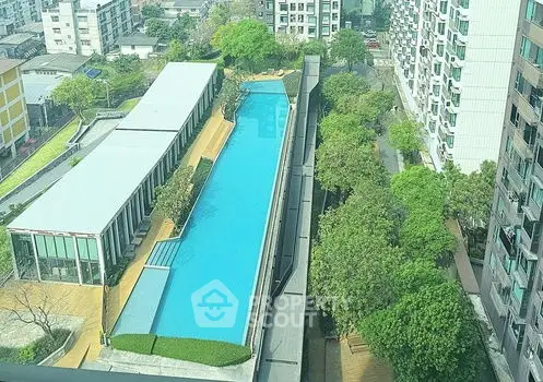 Stunning aerial view of modern apartment complex with large swimming pool and lush greenery.