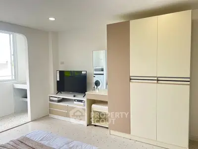 Modern bedroom with sleek wardrobe and TV unit, bright and airy ambiance.