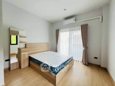 Spacious bedroom with modern wooden furniture and large window for natural light.