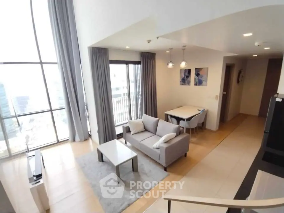 Spacious modern living room with high ceilings and large windows in a luxury apartment.