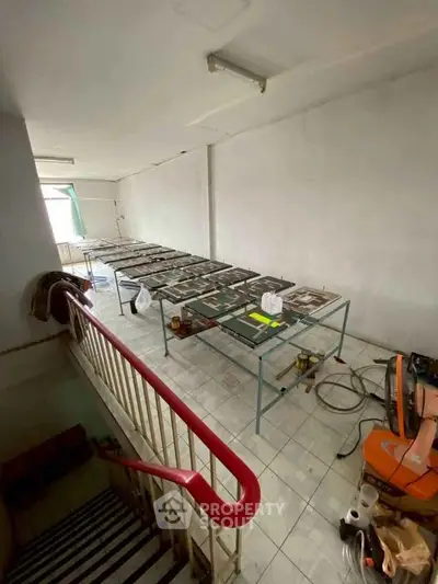Spacious interior with tiled flooring and metal tables, ideal for creative workspace or storage.