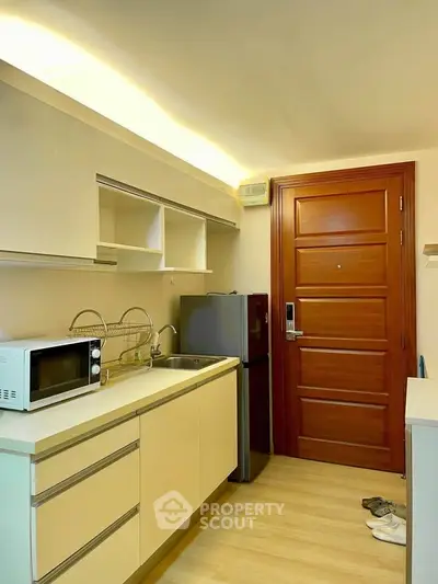 Modern kitchen with sleek cabinetry, microwave, and compact fridge in a cozy apartment setting.
