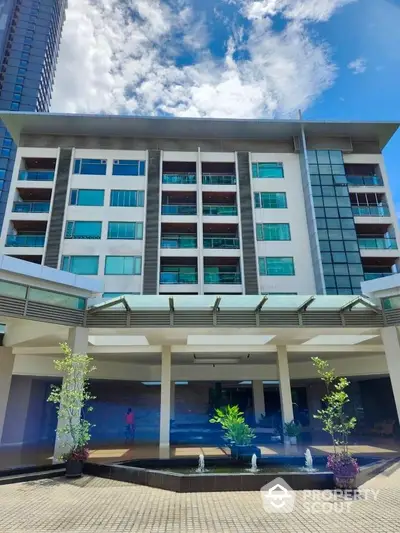 Modern multi-story building with glass facade and landscaped entrance