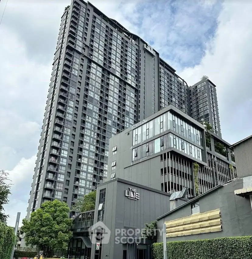 Modern high-rise condominium with sleek design and lush greenery in urban setting.
