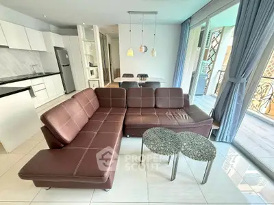 Modern open-plan living room with stylish brown leather sofa and elegant kitchen area.