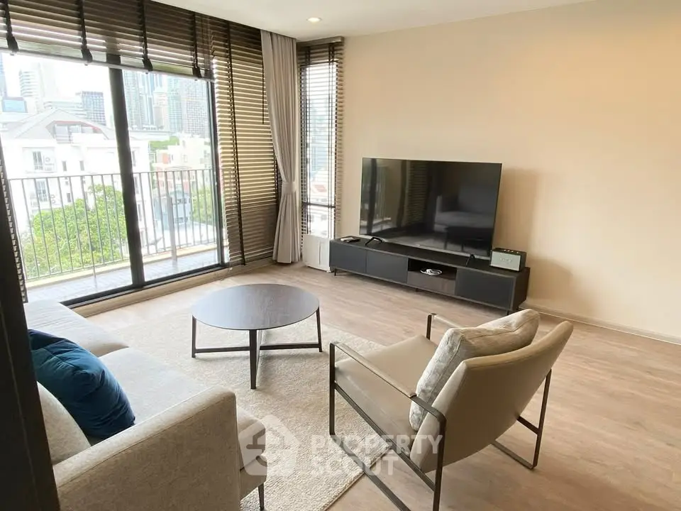 Modern living room with large windows and city view, featuring stylish furniture and a flat-screen TV.