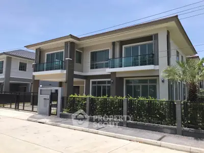 Modern two-story house with large windows and balcony in a suburban neighborhood.