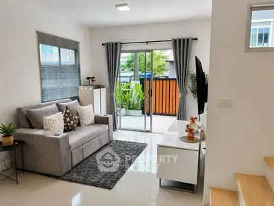 Modern living room with cozy sofa, stylish decor, and sliding glass doors leading to a small balcony.