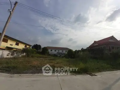 Vacant land plot with potential for development in a residential area, surrounded by houses and greenery.