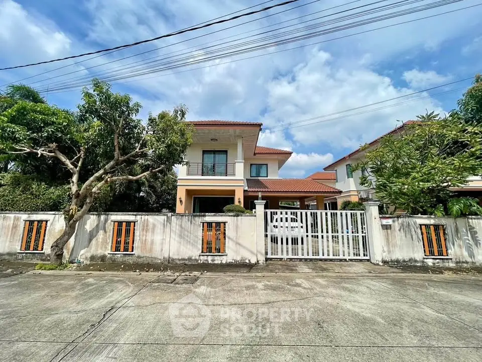 Charming two-story house with gated entrance and lush greenery, perfect for family living.