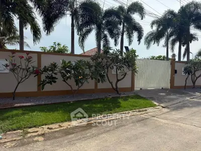 Charming gated entrance with lush greenery and palm trees, perfect for a serene residential setting.