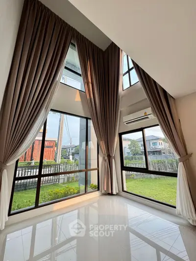 Spacious corner unit with large windows and garden view, featuring elegant curtains and high ceilings.