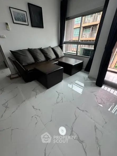 Modern living room with sleek marble flooring and stylish dark sofa set near large window.