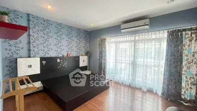 Spacious bedroom with modern decor and large windows for natural light.