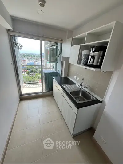 Modern kitchen with balcony view, featuring sleek cabinetry and stainless steel sink.
