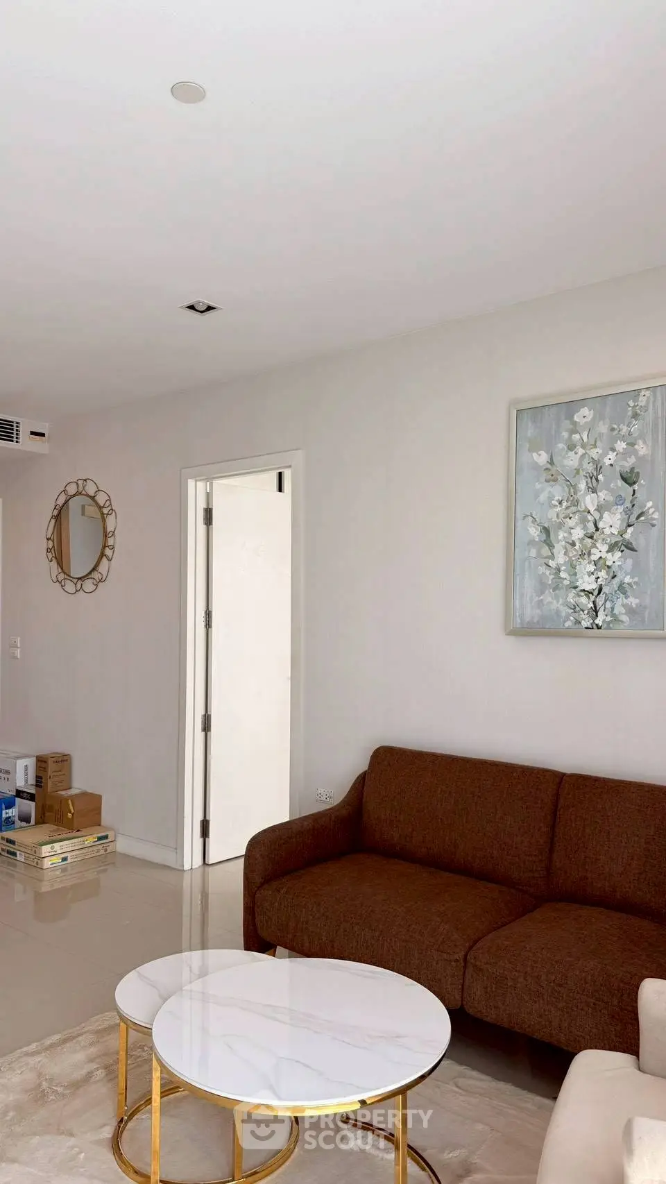 Modern living room with brown sofa, elegant wall art, and stylish coffee tables.
