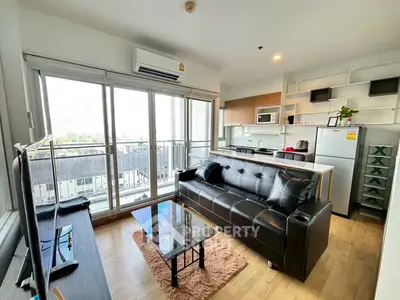 Modern living room with balcony, sleek kitchen, and stylish decor in urban apartment.