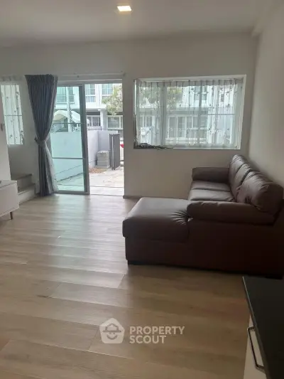 Spacious living room with modern sofa and large windows offering natural light.