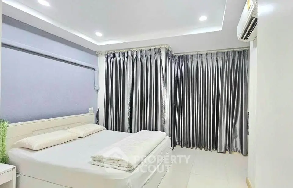 Spacious bedroom with modern decor and elegant curtains, featuring a comfortable bed and ambient lighting.