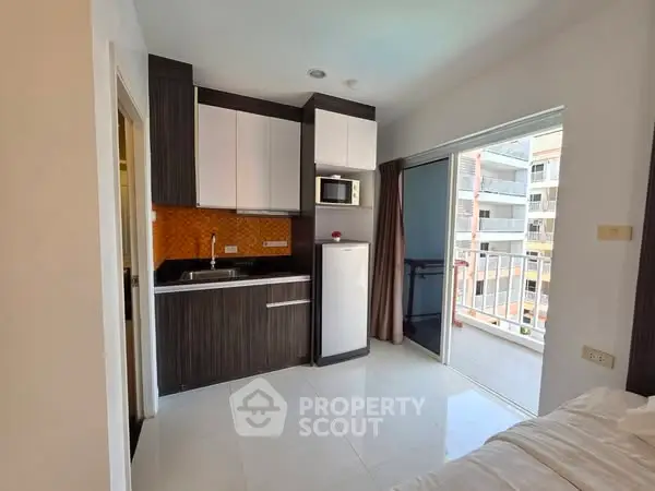 Modern studio apartment with compact kitchen and balcony view