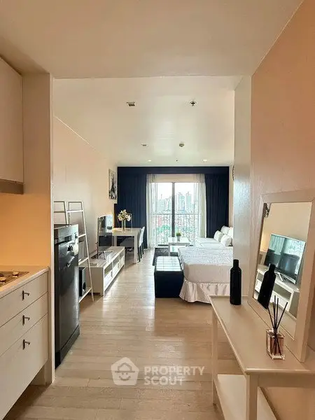 Modern studio apartment with open layout and city view, featuring sleek kitchen and cozy living area.
