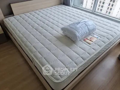 Spacious bedroom with large bed and city view window, perfect for relaxation.