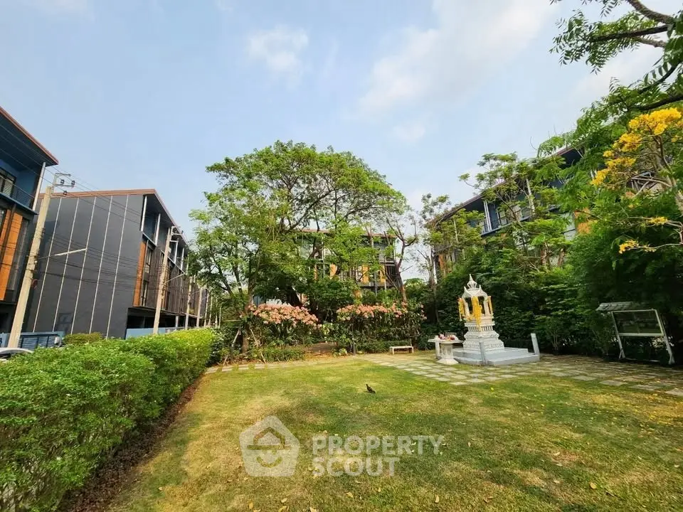 Beautiful garden view with lush greenery and modern buildings in the background.