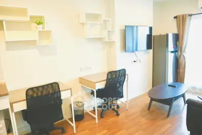 Modern study area with desks, chairs, and wall-mounted TV in a bright apartment.