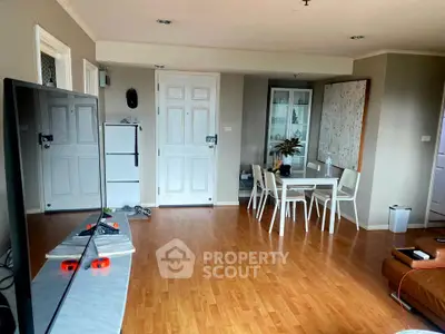 Spacious living room with modern decor and wooden flooring, featuring a dining area and ample natural light.