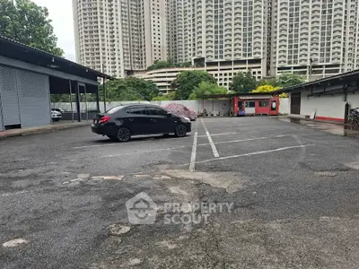 Spacious parking lot with high-rise buildings in the background, ideal for urban living convenience.