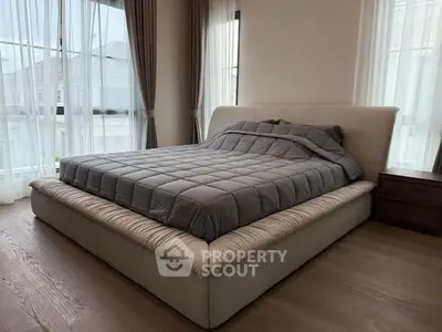 Spacious bedroom with large bed and natural light from floor-to-ceiling windows.