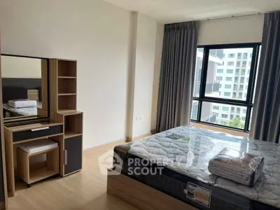 Spacious bedroom with modern furniture and large window offering city view