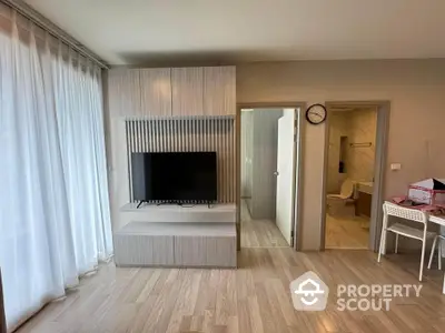 Modern living room with TV unit and view into bathroom, featuring sleek wooden flooring.