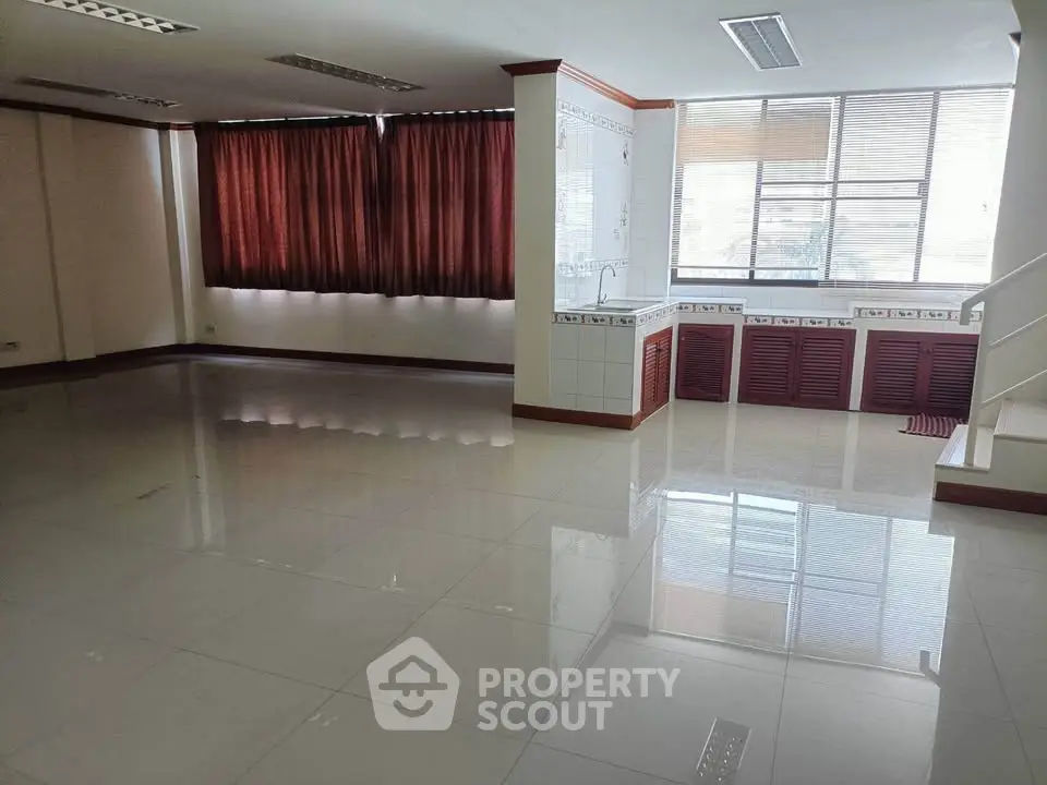 Spacious open-plan living area with large windows and tiled flooring