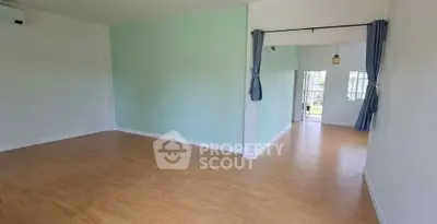 Spacious empty living room with wooden flooring and large windows for natural light.