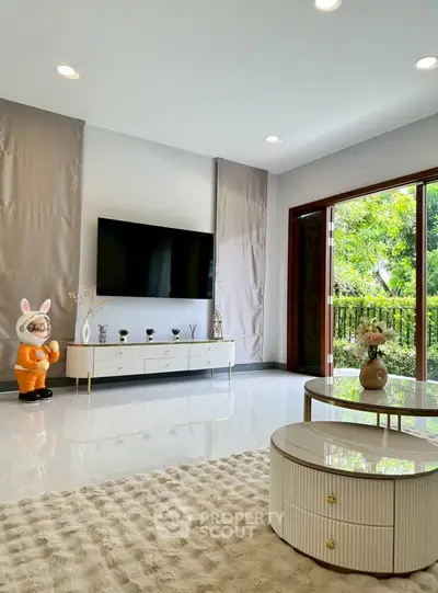 Elegant living room with modern decor, large TV, and garden view through sliding doors.
