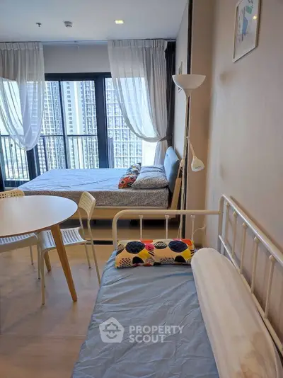 Modern studio apartment with large windows and stylish decor, offering a cozy and bright living space.