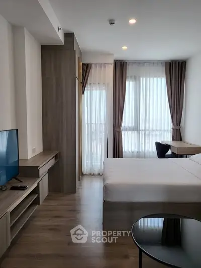 Modern bedroom with sleek design and natural light, featuring a cozy workspace and stylish decor.