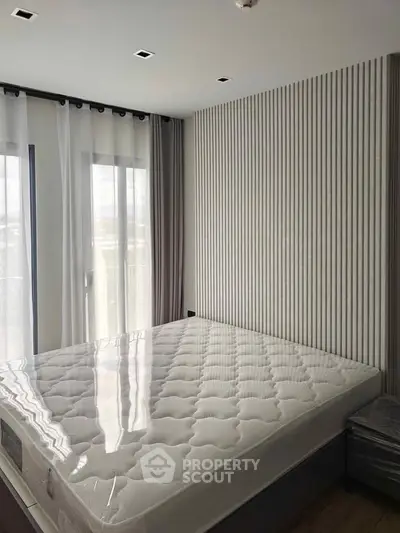 Modern bedroom with stylish wall paneling and large windows for natural light.