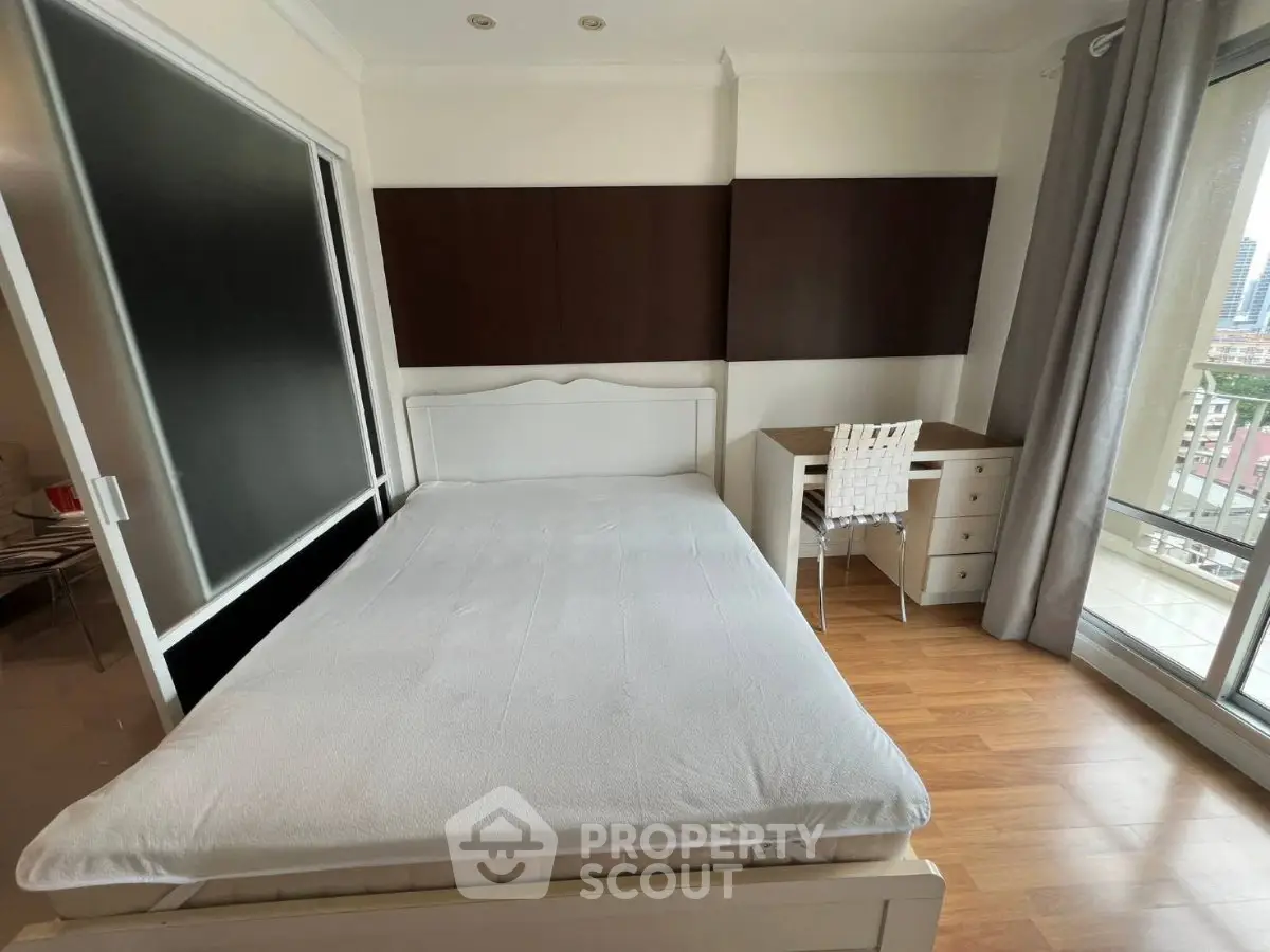 Spacious bedroom with wooden flooring and balcony view in modern apartment