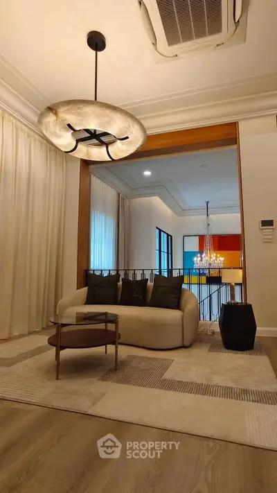 Elegant living room with modern chandelier and cozy seating area, perfect for relaxation and entertaining.