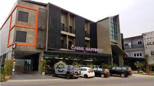 Modern commercial building with sleek design and ample parking space.
