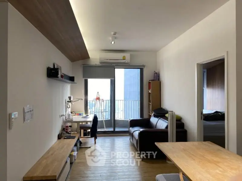 Modern living room with balcony view, featuring sleek furniture and natural light.