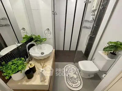 Modern bathroom with stylish sink and shower, featuring elegant decor and greenery.