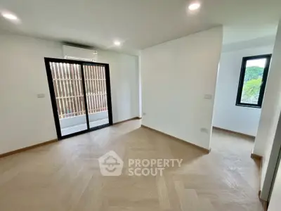 Spacious modern living room with wooden flooring and large windows for natural light.