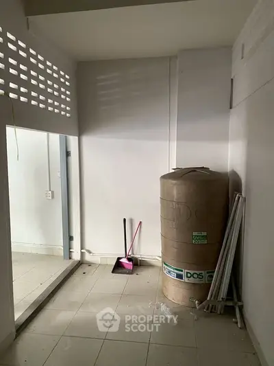 Spacious storage area with water tank and cleaning tools, ideal for utility use in a residential property.