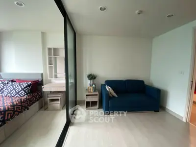 Modern studio apartment with cozy living area and stylish bedroom separated by glass partition.