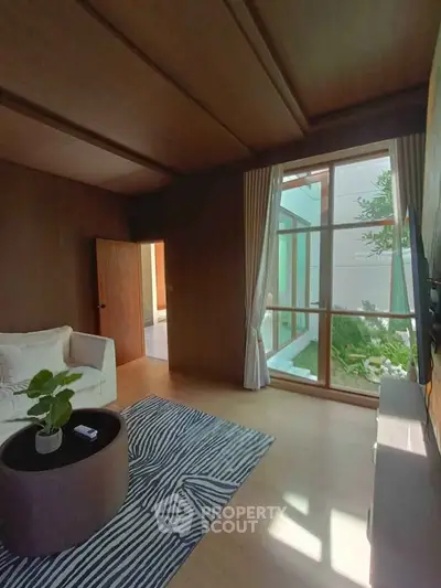 Elegant living room with large window and cozy seating area, perfect for relaxation.